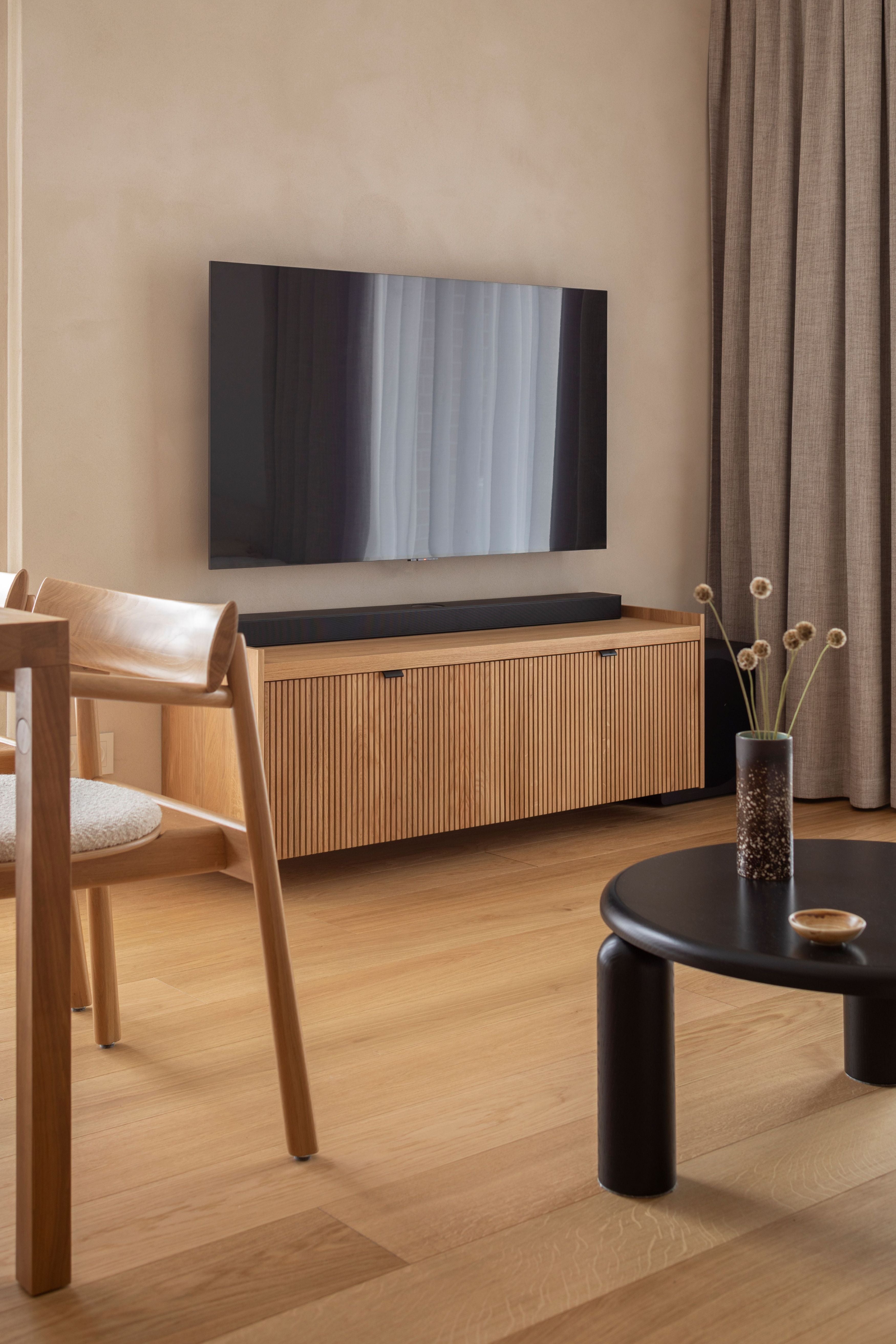 Une console murale en bois avec des lattes verticales, associée à un miroir mural rond et une étagère en bois au-dessus.