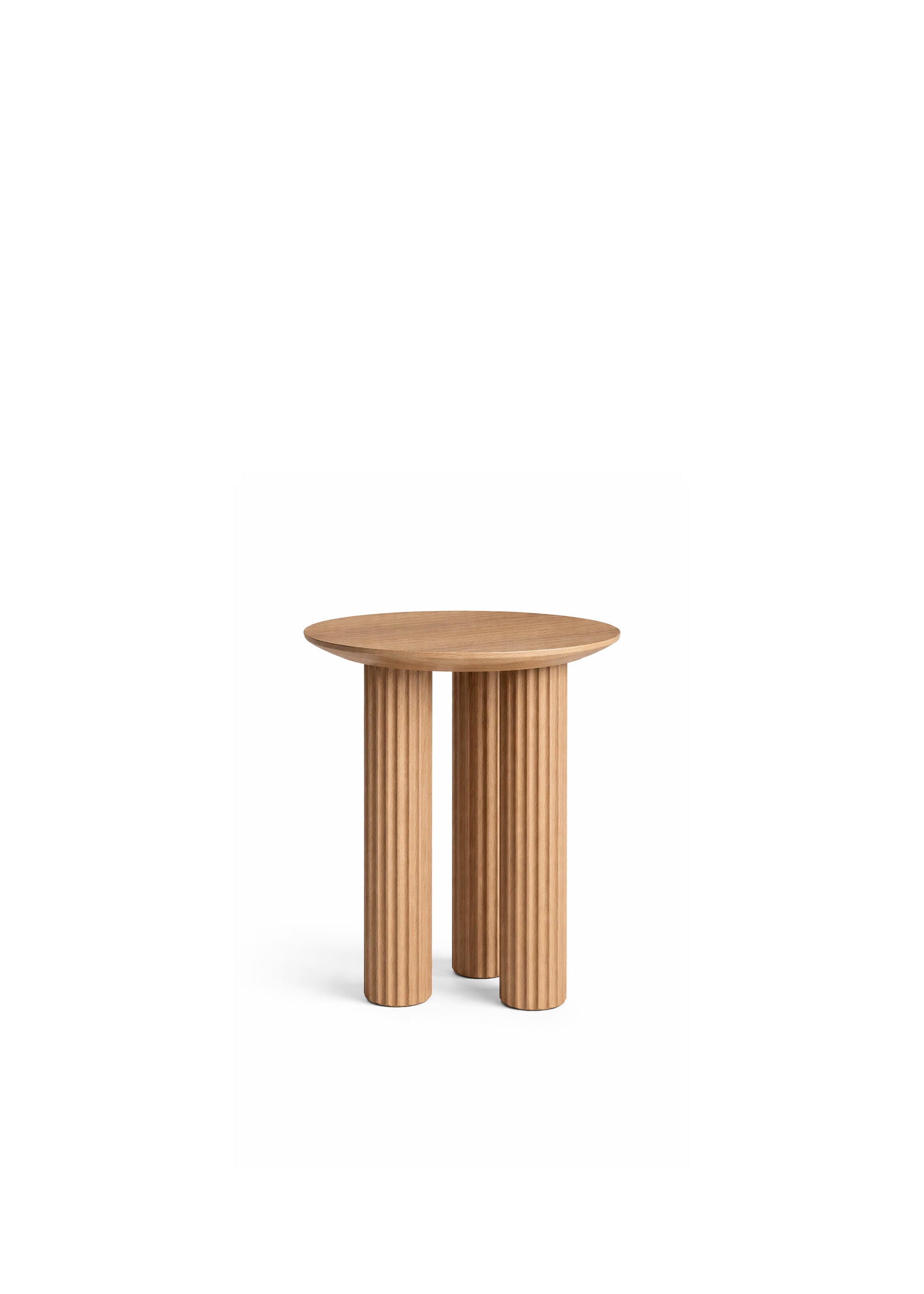 A wooden side table with grooved cylindrical legs positioned next to a modern grey lounge chair and floor lamp.