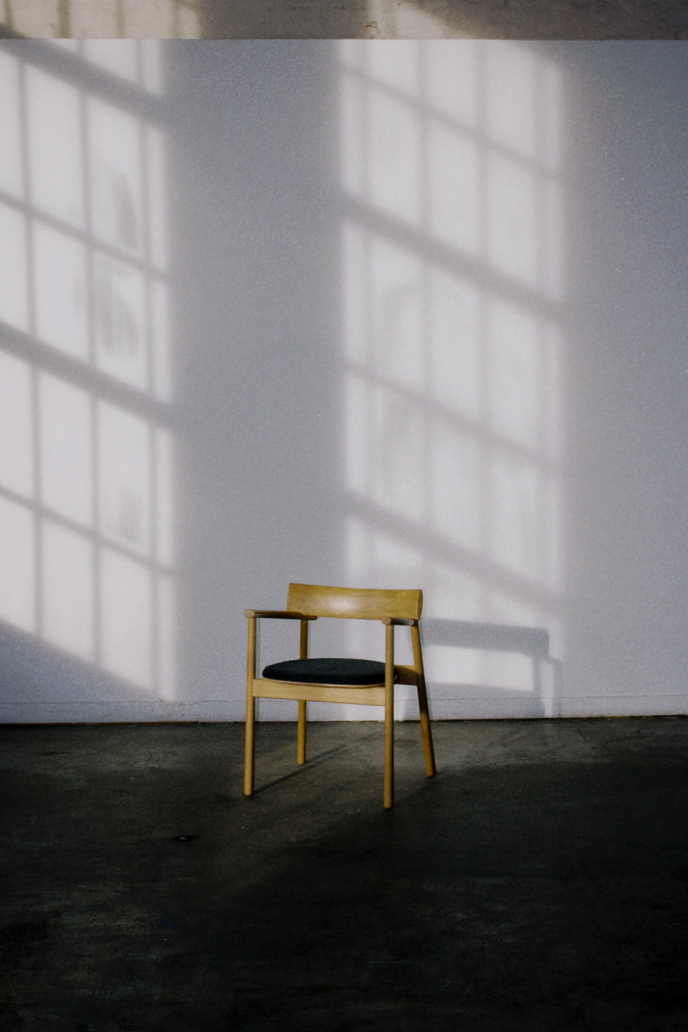 Lounge chair made of light wood with a round dark seat cushion